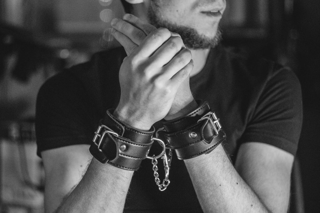 A man wearing leather hand-cuffs.